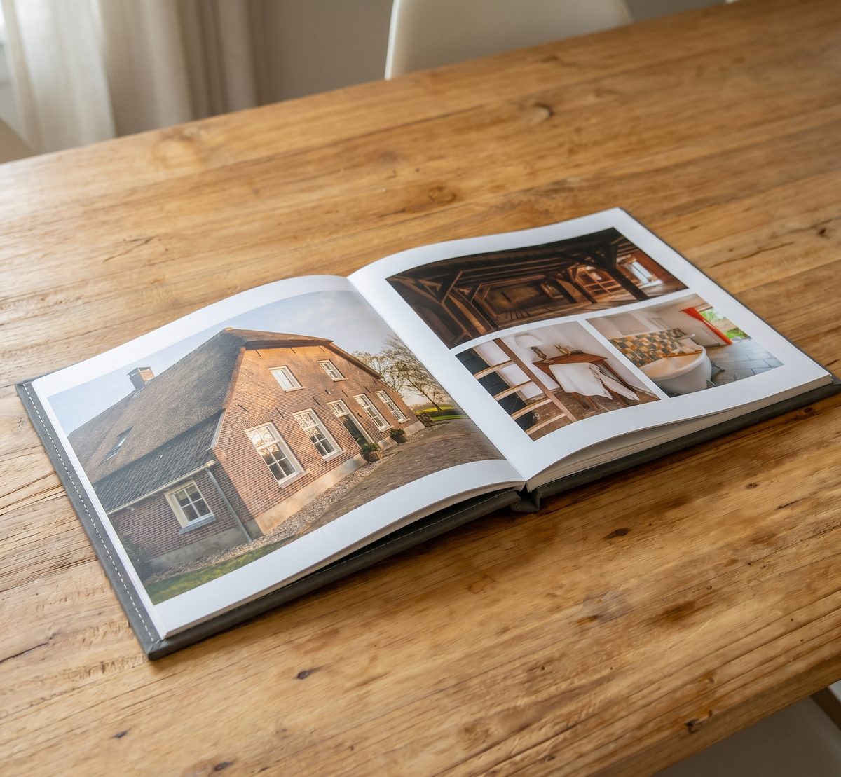 Opengeslagen fotoboek op een houten tafel met foto's van een woonhuis en het interieur